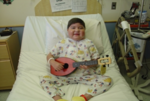 Boy with guitar in hospital bed